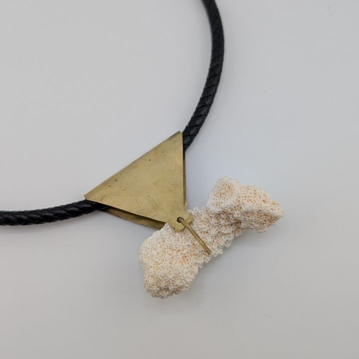 Necklace with a geometric pendant and textured stone on a light gray background