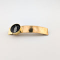 Gold hair clip with black and white fern on a light gray background
