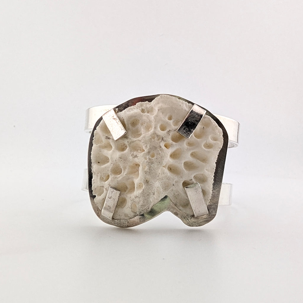 Top view of a silver arm cuff with bone set on top on a white background.