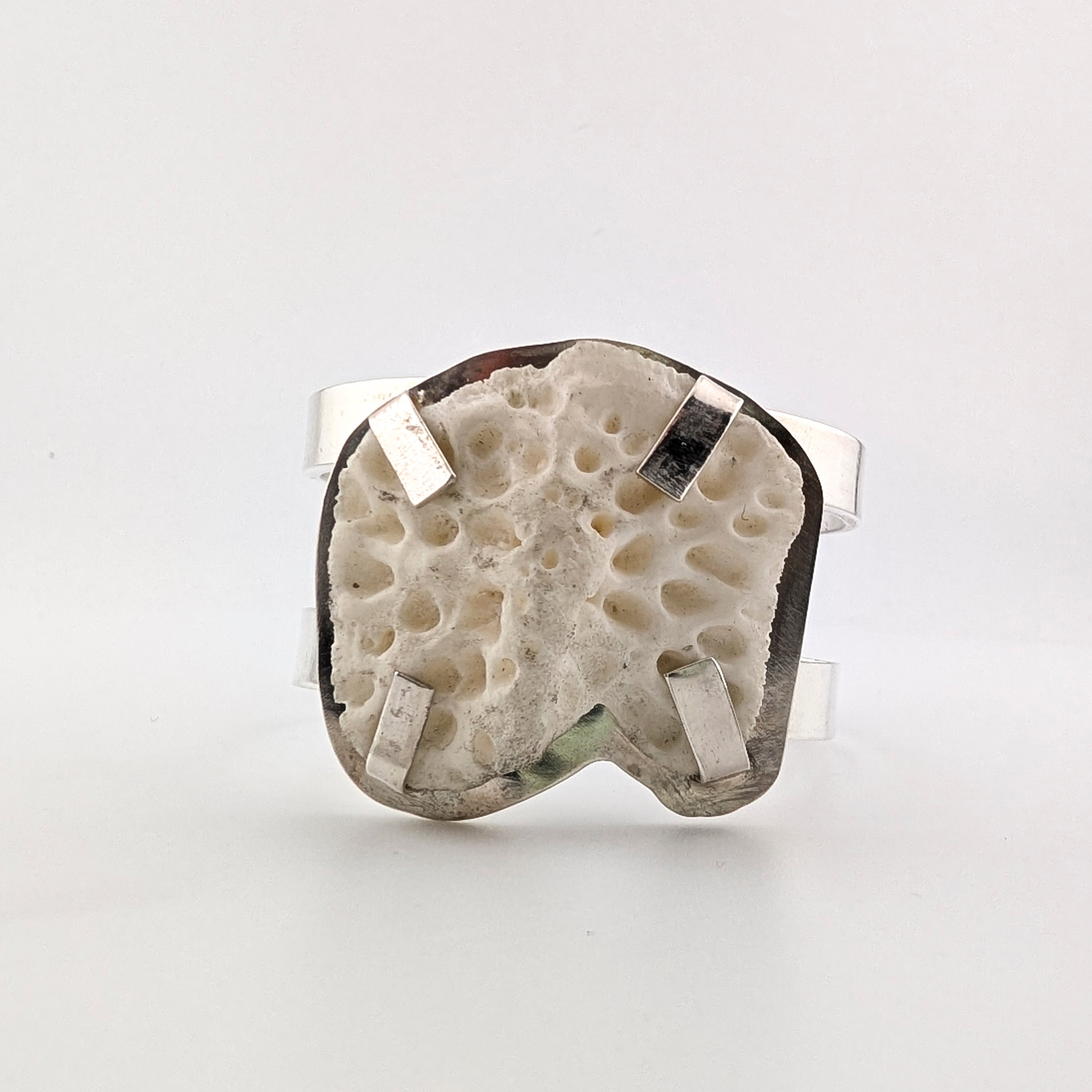 Top view of a silver arm cuff with bone set on top on a white background.