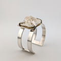 Silver arm cuff with bone set on top on a white background.