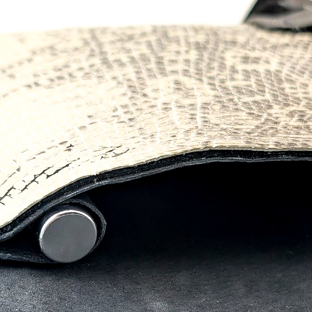 Macro shot of a black and white leather lizard clutch with interior pocket for perfume vial.
