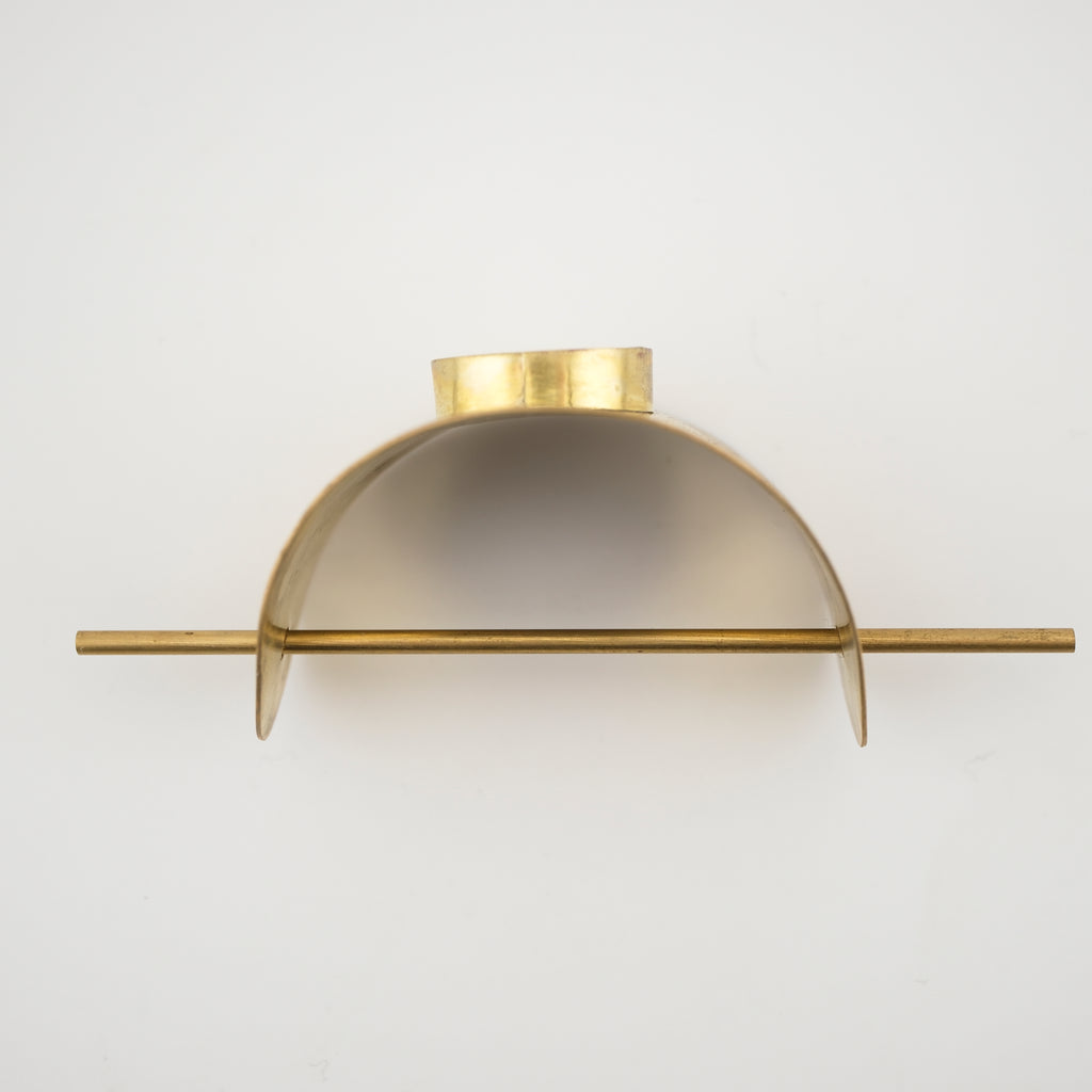 Brass curved hair cuff with brass pin against a white background.