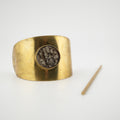 Gold cuff hair piece with a central setting of lizard skin on a white background.