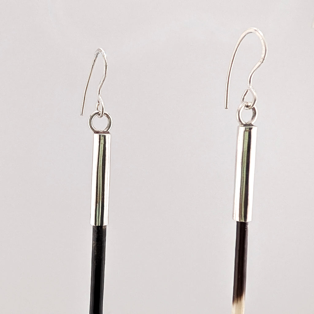 Silver and brown porcupine quill earrings on a light gray background