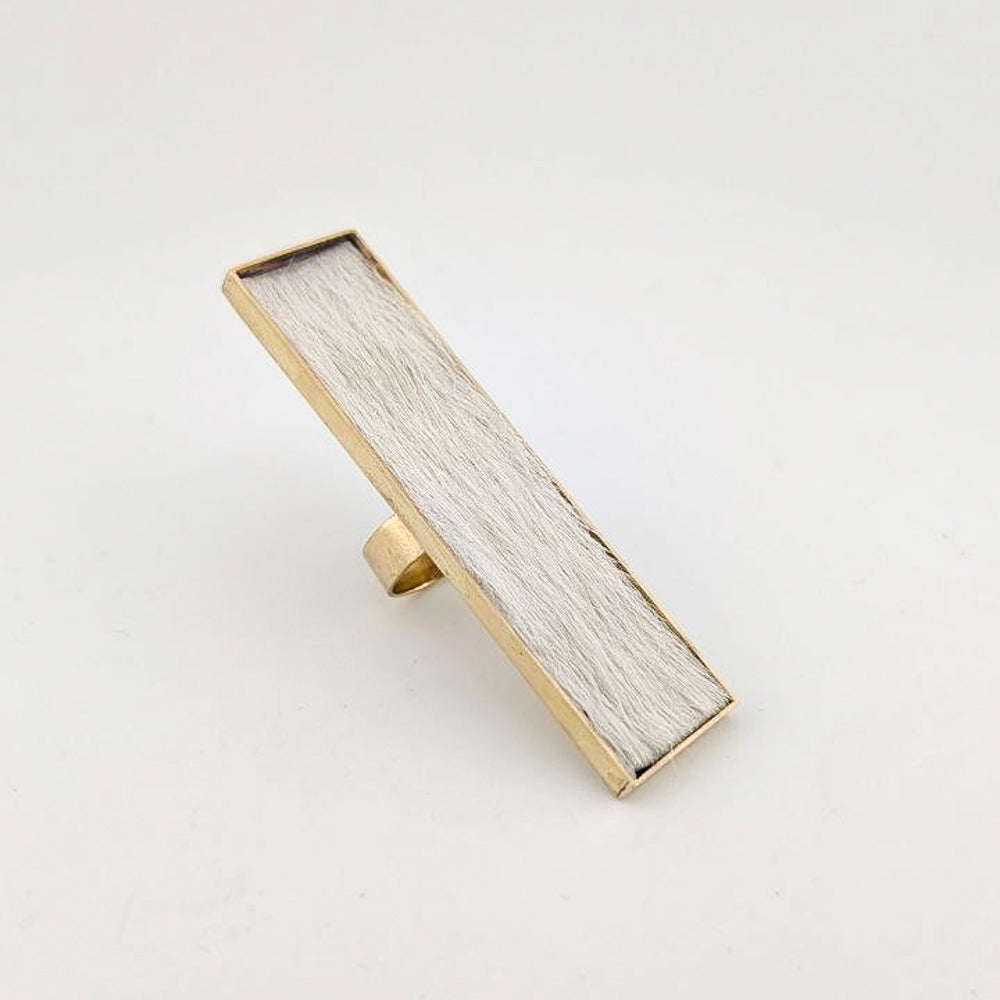 Brass rectangular ring with white cowhide embedded inside against a white background.