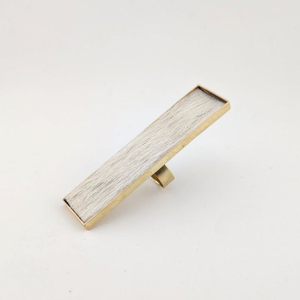 Brass rectangular ring with white cowhide embedded inside against a white background.