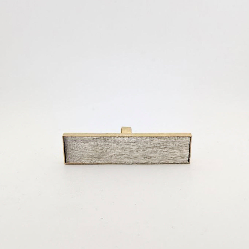 Brass rectangular ring with white cowhide embedded inside against a white background.