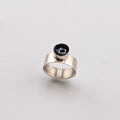 Silver ring with a black and blue butterfly wing on a light gray background