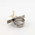 Textured silver ring with a bone on a white background