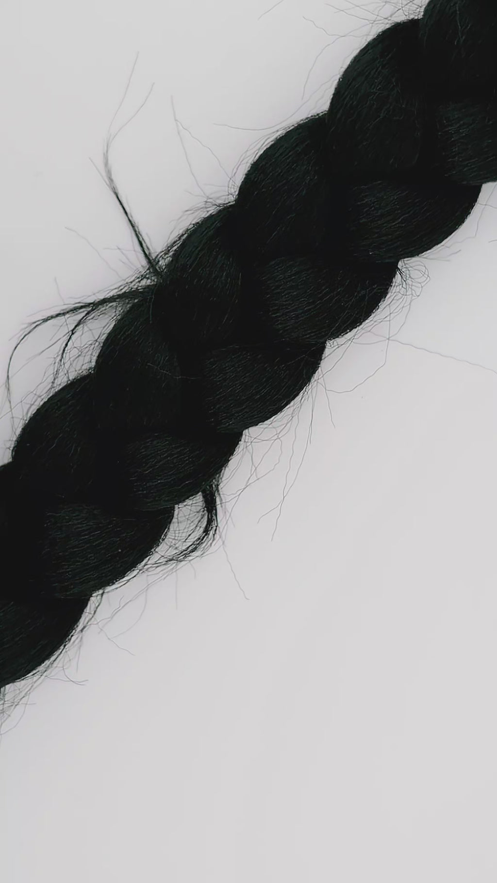 Hands putting on a blue and silver hair pin on a thick black braid of hair against a white background.
