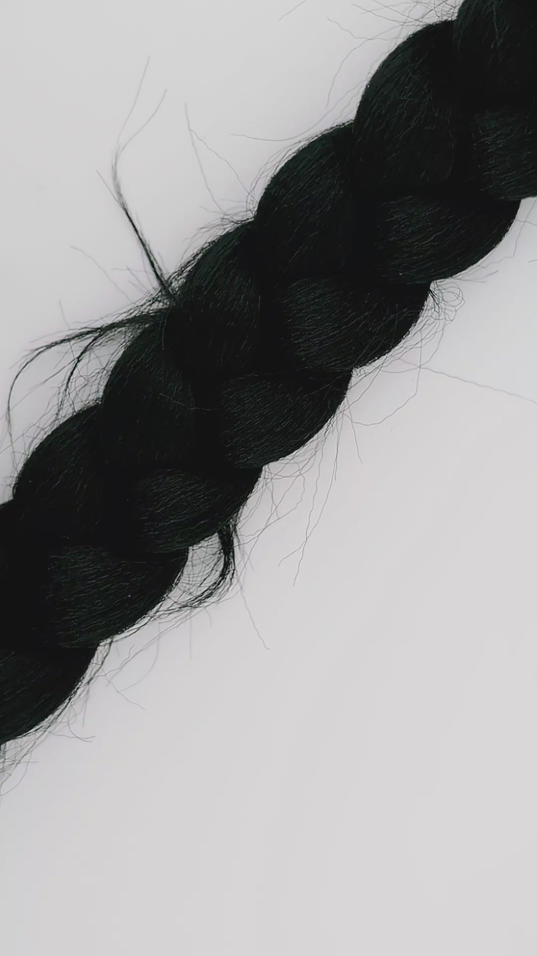 Hands putting on a blue and silver hair pin on a thick black braid of hair against a white background.